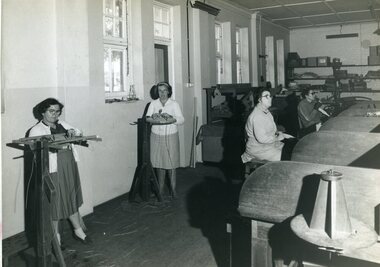 Four women standing or sitting at various workstations