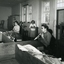 Four women standing or sitting at various workstations