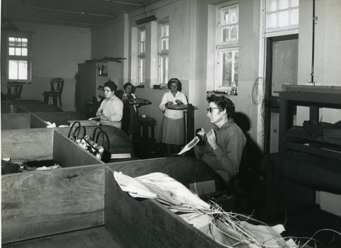 Four women standing or sitting at various workstations