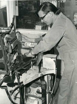Man standing over machine that puts bristles into broom heads