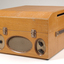 Wooden box with metal grill in front and two clasps.  To the side is a leather strap handle.