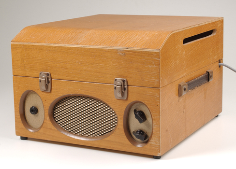 Wooden box with metal grill in front and two clasps.  To the side is a leather strap handle.