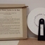 Cardboard box stands next to round wheel with Braille, held by a black plastic handle