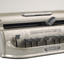Metal Braille writer with nine grey keys, carriage return key and paper rollers on either side