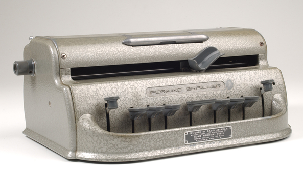 Metal Braille writer with nine grey keys, carriage return key and paper rollers on either side