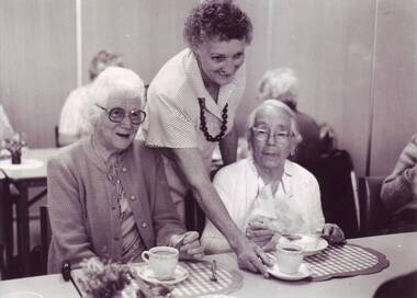 Woman places a cup of tea down between two older women