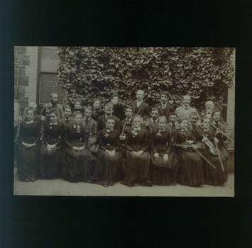 Large group of men and women, some holding instruments, outside the RVIB building.