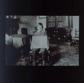 Boy holding a Taylor slate towards camera in his lap