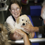 Woman holding SEDA puppy as hands reach out to pat