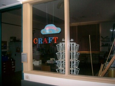 Craft sign in window of darkened room, made of large cut out letters
