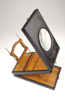 1 wooden box with fold out top and inset glass magnifier.