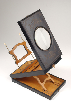 1 wooden box with fold out top and inset glass magnifier.