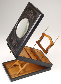 1 wooden box with fold out top and inset glass magnifier.