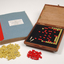 Braille book and wooden box containing yellow and red rubber markers that fit into the grid inset in the box