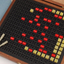 Braille book and wooden box containing yellow and red rubber markers that fit into the grid inset in the box