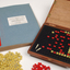 Braille book and wooden box containing yellow and red rubber markers that fit into the grid inset in the box