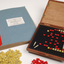 Braille book and wooden box containing yellow and red rubber markers that fit into the grid inset in the box