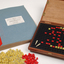 Braille book and wooden box containing yellow and red rubber markers that fit into the grid inset in the box
