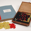 Braille book and wooden box containing yellow and red rubber markers that fit into the grid inset in the box