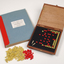Braille book and wooden box containing yellow and red rubber markers that fit into the grid inset in the box