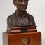 Bronze bust of Louis Braille on wooden mount.