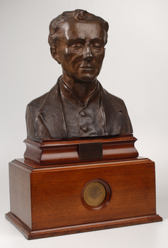 Bronze bust of Louis Braille on wooden mount.