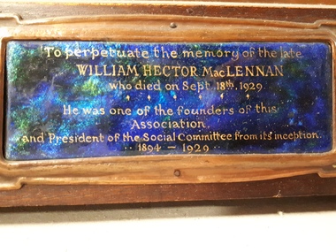Brown wooden memorial tablet with inset of copper and photograph.