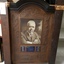 Brown wooden memorial tablet with inset of copper and photograph.