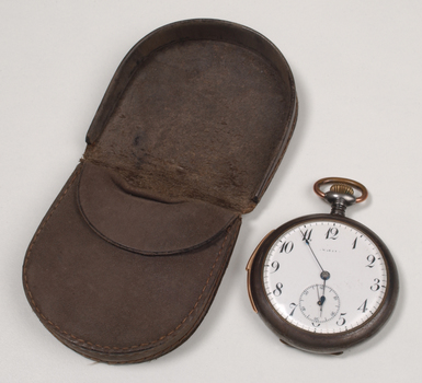 Brown case holding pocket watch with Braille markings