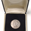 Silver coin with profile of short-haired woman turned to the left inside velvet box