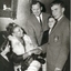 Seated woman shakes hand with schoolboy, whilst two school girls and a teacher look on