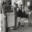 Three school children on pavement outside theatre with two cast members and RVIB combi beside them