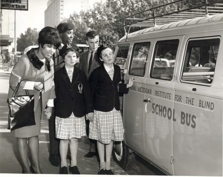 Two cast members with three school children on pavement outside theatre, standing next to RVIB combi