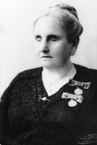 Woman with hair in bun and black dress wearing medals