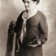 Woman holding back of chair as she stand facing away from camera