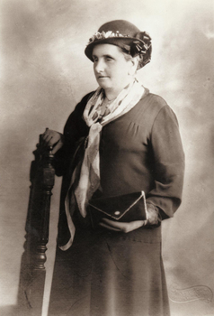 Woman holding back of chair as she stand facing away from camera