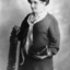 Woman holding back of chair as she stand facing away from camera