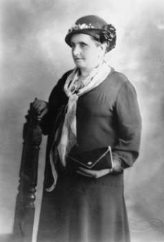 Woman holding back of chair as she stand facing away from camera