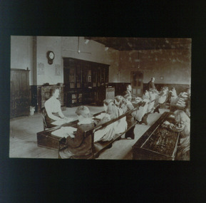 Three teachers sit or stand in front of rows of students