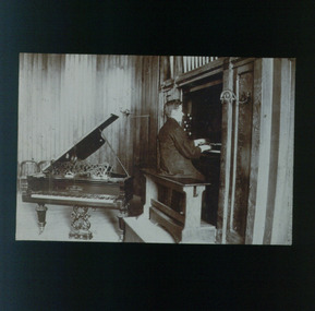 Teenage boy plays an organ with a piano behind him