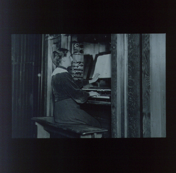 Female organist touches braille music sheet as she plays the organ