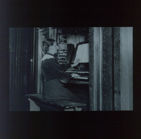 Female organist touches braille music sheet as she plays the organ