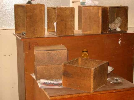 Wooden boxes inside Raleigh Street house with ashtray, drink bottle and bowl upon table