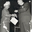 Mrs Tutton shaking hands with a suited man and receiving something, possibly a badge