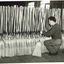 Man kneeling as he stacks completed brooms
