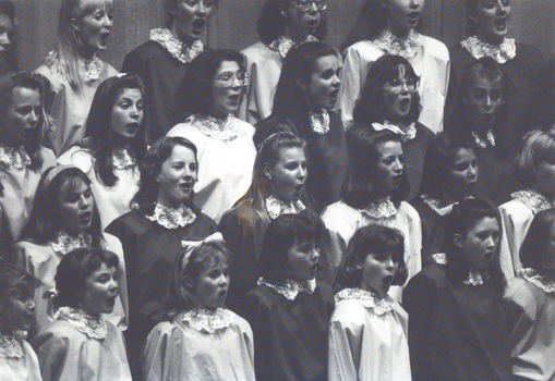 Children singing whilst wearing robes and lace collar