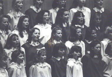 Children singing whilst wearing robes and lace collar