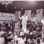 Mark Holden smiling as he croons on stage in a white suit