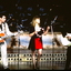 A three piece band, two guitarists and one singer, play on stage