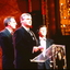 Two CEOs at the lectern whilst Ray Martin watches on